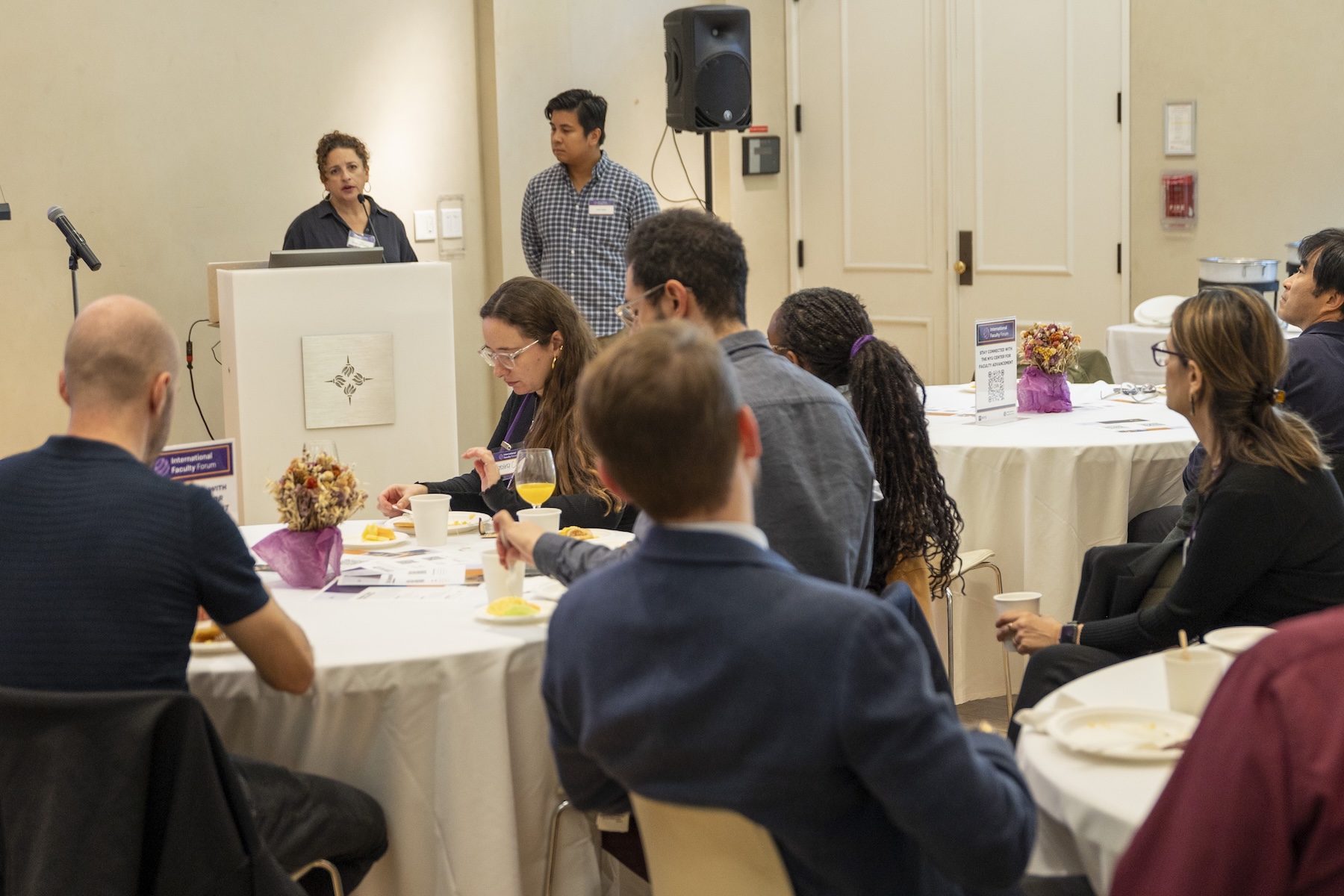 Conference attendees seated at round tables listening to a speaker