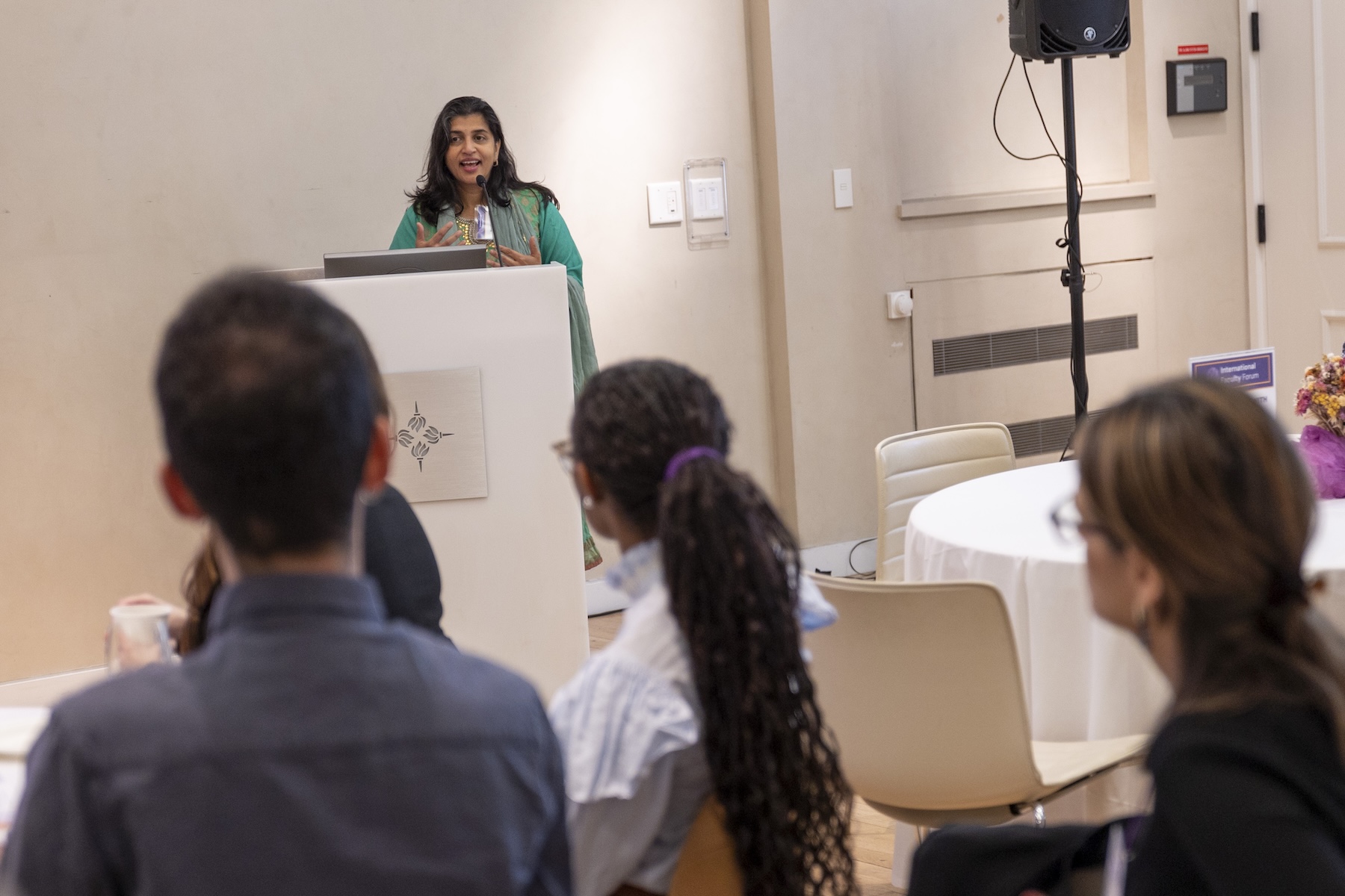 A speaker at a podium addressing a seated audience