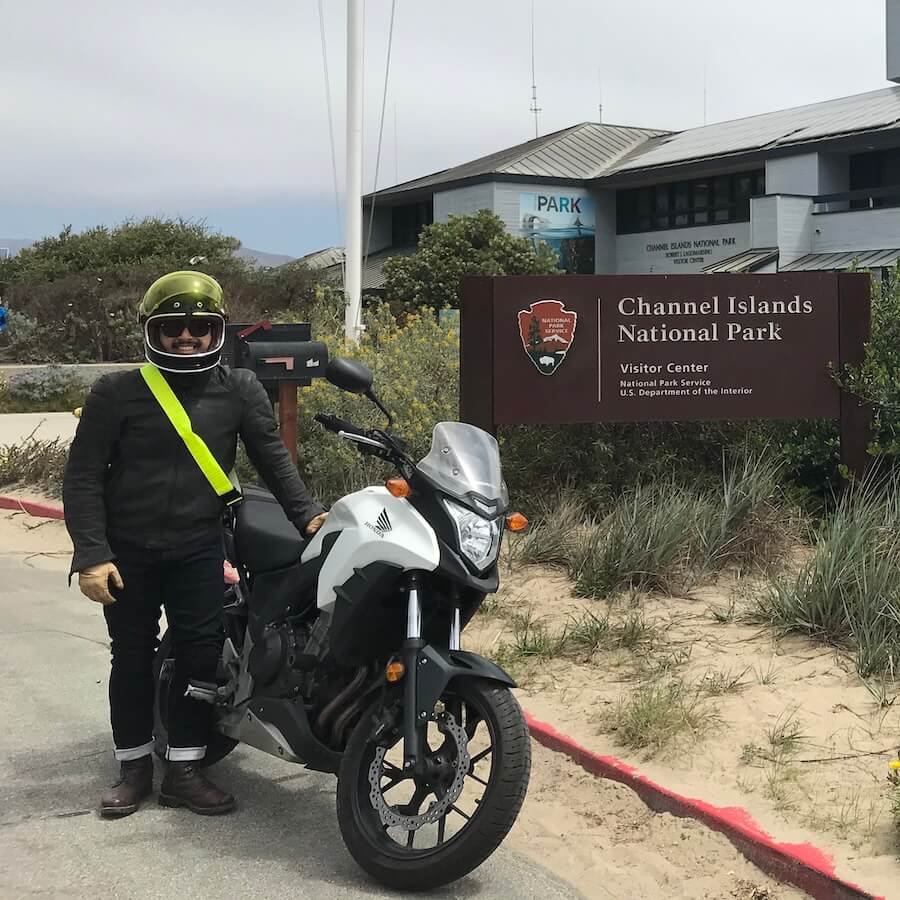 Mike Hoa Nguyen standing next to a motorcycle in front of the Channel Islands National Park visitor center